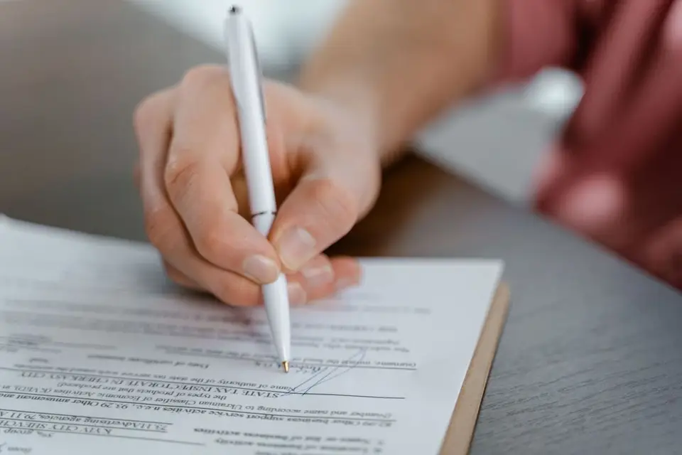 Main signant un document officiel au stylo, posé sur un bureau
