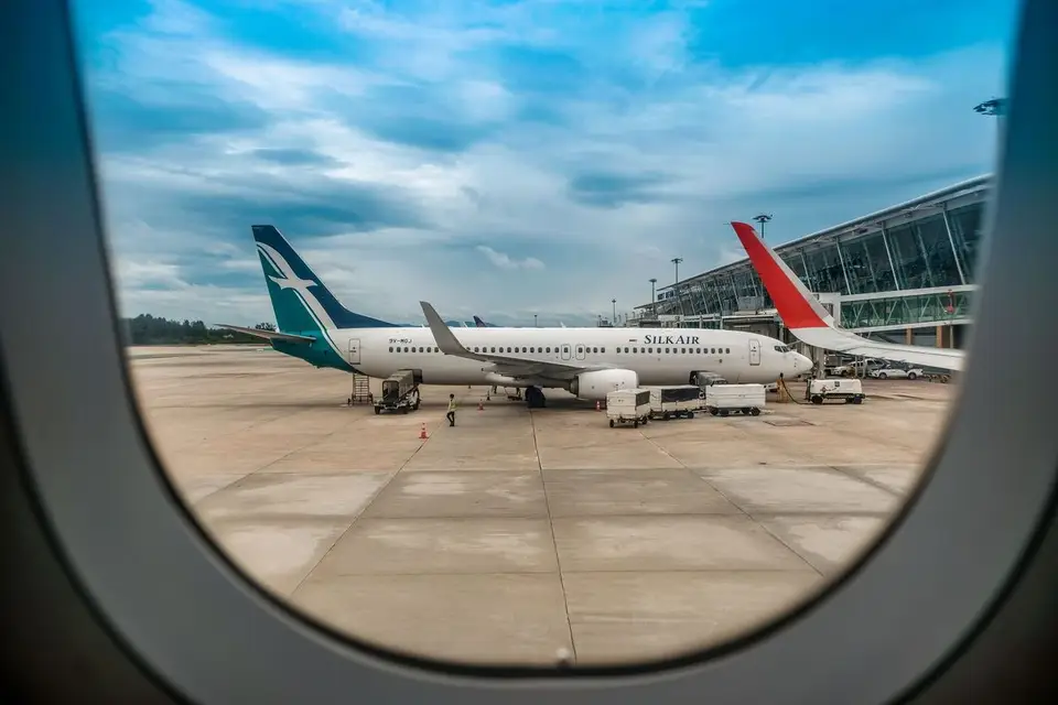Avions sur le tarmac vus depuis le hublot d'un avion, sous un ciel dégagé